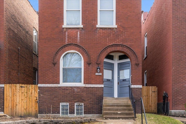 view of front facade featuring brick siding and fence