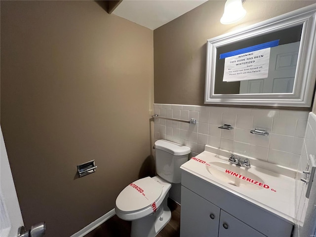 half bath featuring vanity, tile walls, and toilet