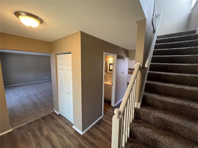 staircase featuring visible vents, baseboards, and wood finished floors