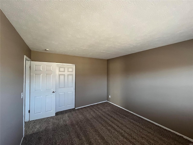 unfurnished bedroom featuring a closet, a textured ceiling, baseboards, and dark colored carpet