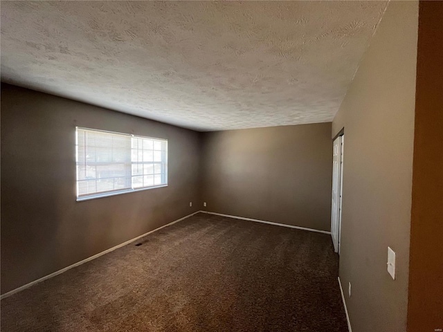 empty room with baseboards, dark carpet, and a textured ceiling