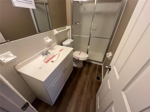 bathroom with vanity, wood finished floors, decorative backsplash, a shower stall, and toilet