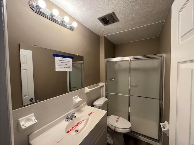 bathroom featuring vanity, visible vents, a stall shower, a textured ceiling, and toilet