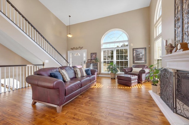 living room featuring a high ceiling, a tile fireplace, and hardwood / wood-style flooring