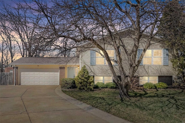 view of front of property with brick siding, a lawn, an attached garage, and concrete driveway