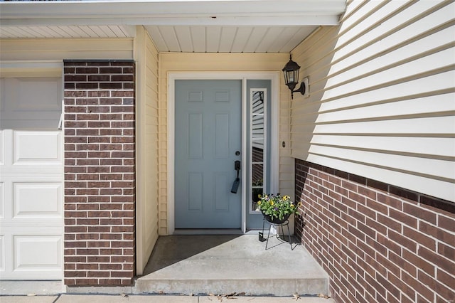 view of exterior entry featuring brick siding and a garage