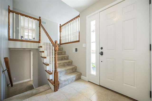 entryway with tile patterned floors, visible vents, baseboards, and stairs