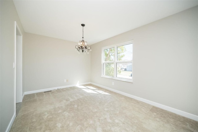 carpeted empty room with a notable chandelier and baseboards