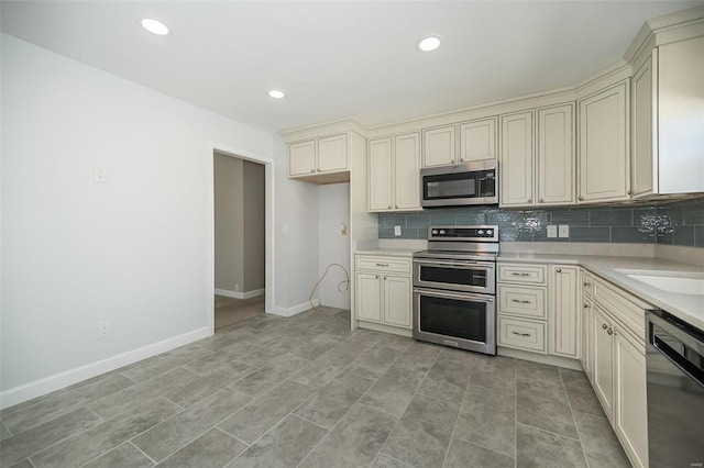 kitchen with tasteful backsplash, baseboards, light countertops, cream cabinets, and stainless steel appliances