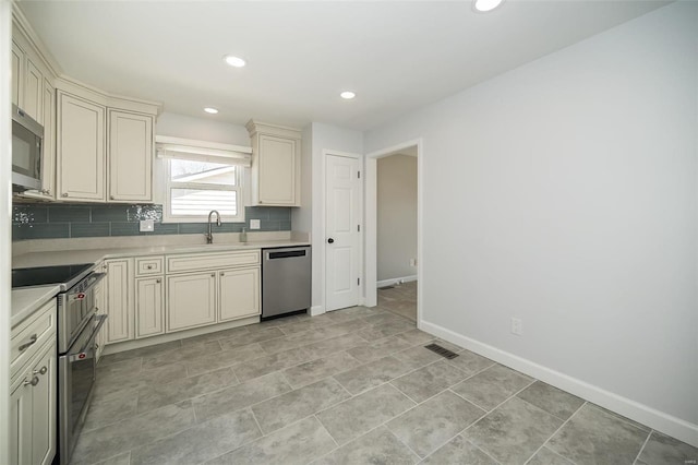 kitchen with appliances with stainless steel finishes, cream cabinets, light countertops, and a sink