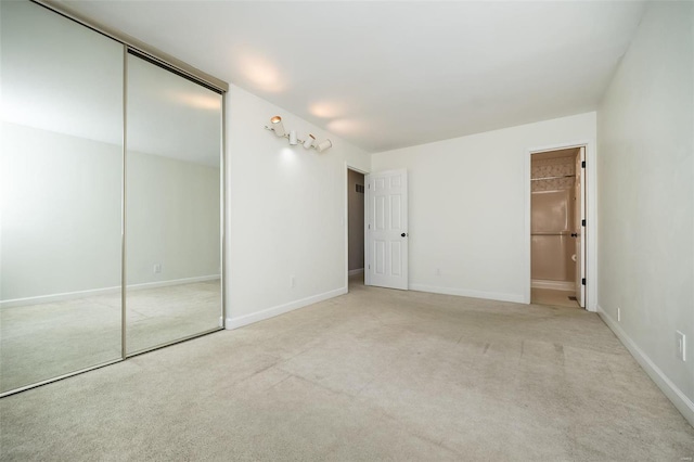 unfurnished bedroom with carpet, baseboards, a closet, and connected bathroom