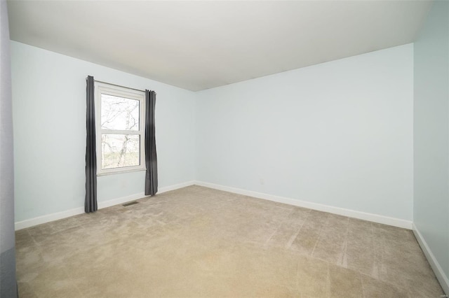 unfurnished room featuring baseboards and light carpet