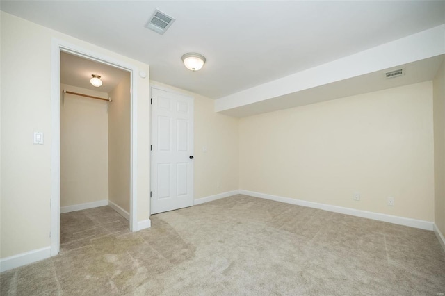 interior space featuring visible vents, baseboards, light colored carpet, and a spacious closet