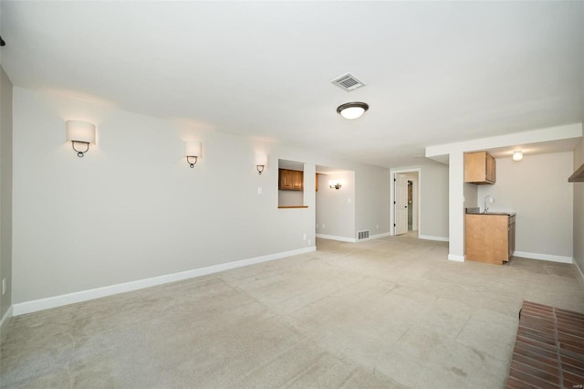 unfurnished living room with visible vents, baseboards, and light carpet