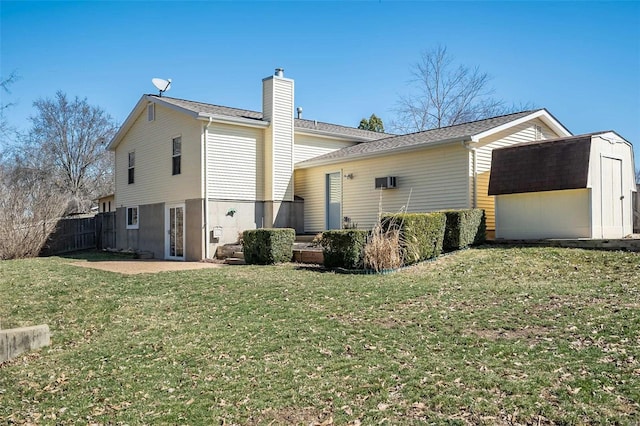 back of house with a chimney, an outdoor structure, a storage unit, a patio area, and a lawn