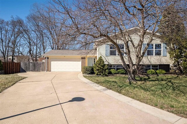 view of front of home featuring brick siding, fence, concrete driveway, a front yard, and an attached garage