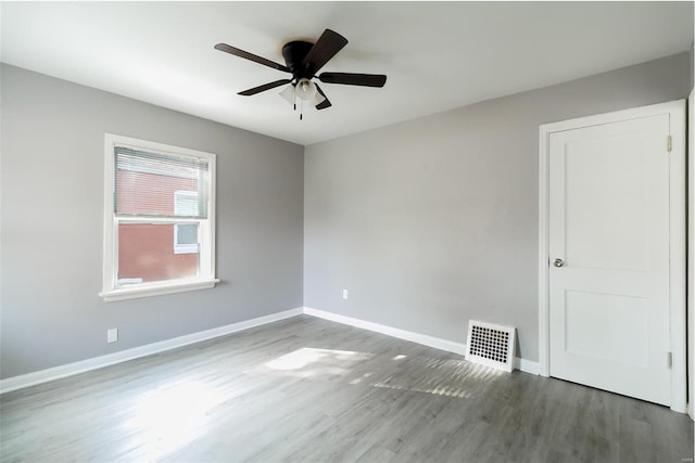 spare room featuring visible vents, ceiling fan, baseboards, and wood finished floors