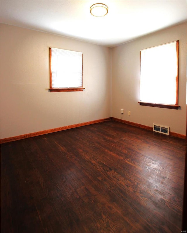 unfurnished room featuring dark wood finished floors, baseboards, and visible vents