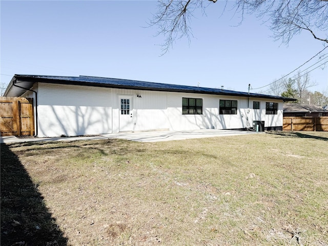 back of property with brick siding, a lawn, a patio, and fence