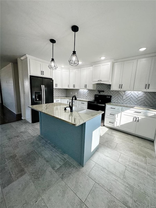 kitchen featuring light stone counters, a sink, black appliances, white cabinetry, and backsplash