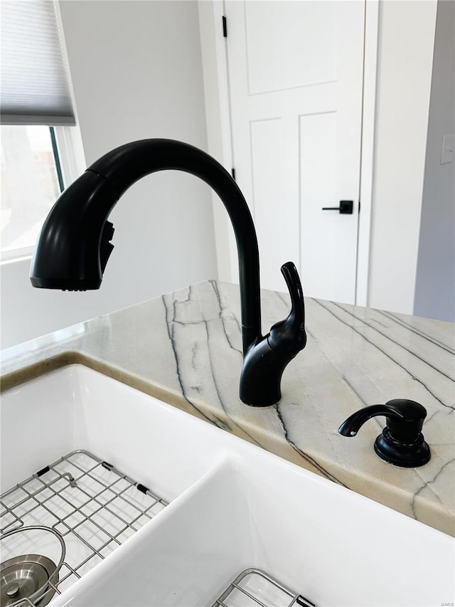 details featuring a sink, light stone countertops, and white cabinets