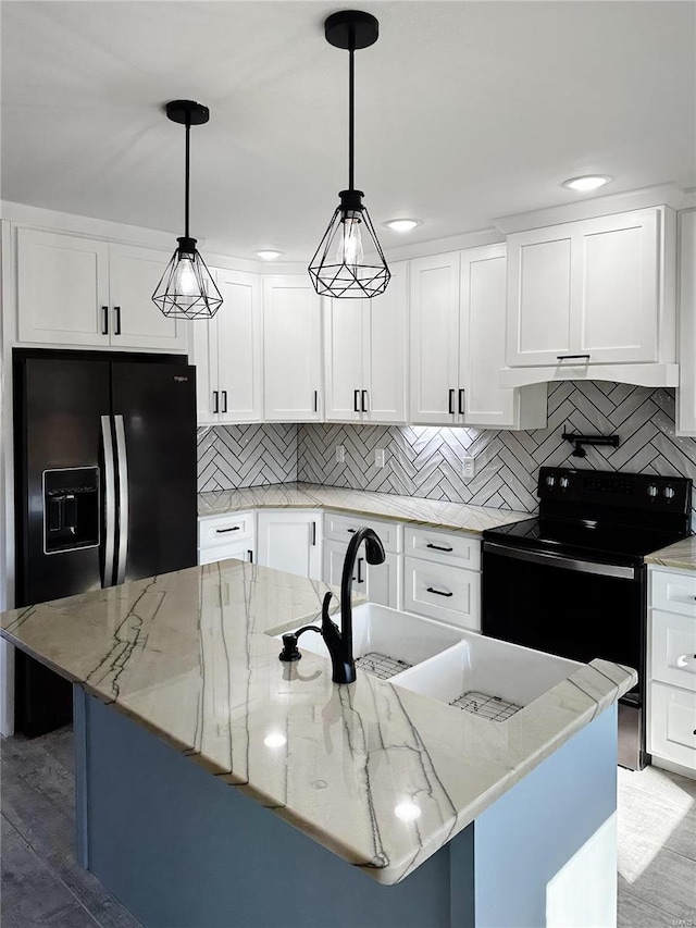 kitchen with black appliances, a center island with sink, tasteful backsplash, white cabinetry, and light stone countertops