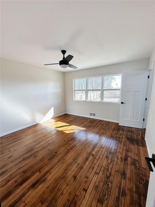 spare room featuring dark wood-type flooring, baseboards, visible vents, and ceiling fan