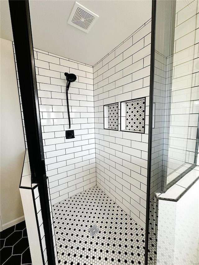 bathroom with tile patterned floors, visible vents, and tiled shower