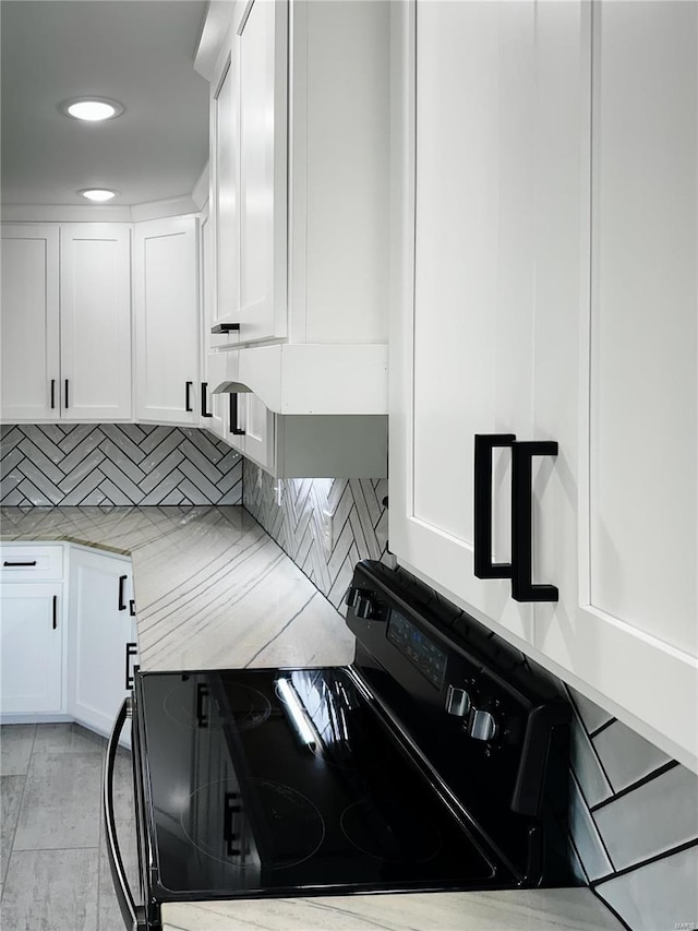 kitchen with decorative backsplash, light countertops, black range with electric cooktop, and white cabinetry