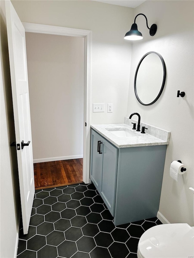 bathroom with tile patterned floors, baseboards, toilet, and vanity