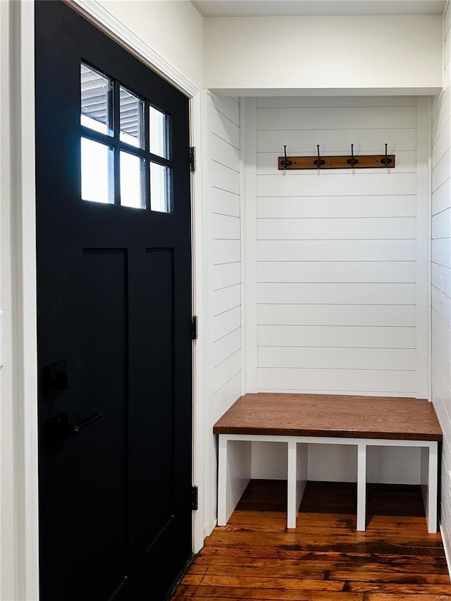 mudroom with dark wood finished floors and wood walls