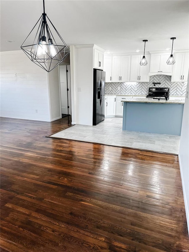 kitchen with wood-type flooring, range with electric cooktop, a chandelier, and black fridge