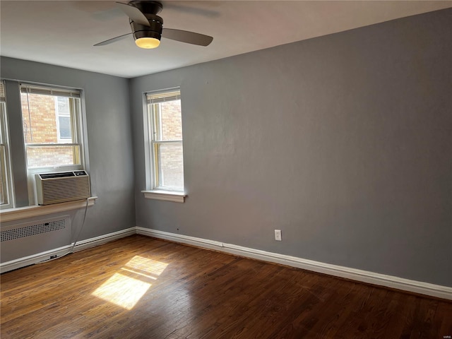 empty room with radiator heating unit, wood finished floors, baseboards, and a wealth of natural light