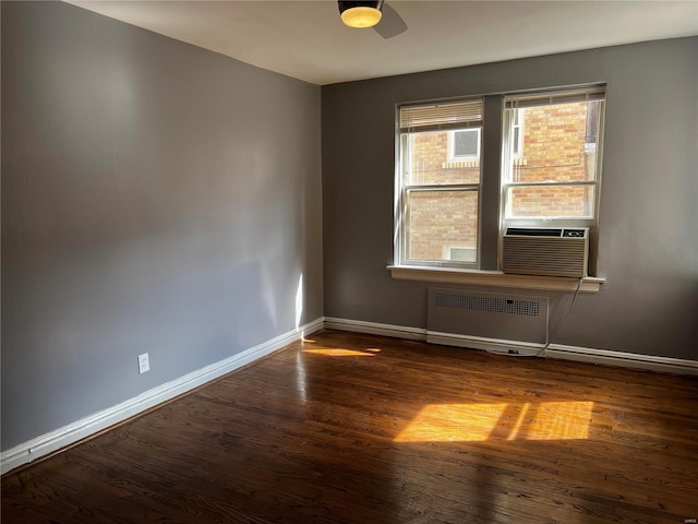 empty room featuring cooling unit, baseboards, radiator, and wood finished floors