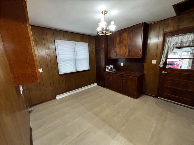 interior space with a chandelier, wood walls, baseboards, and light wood-style floors