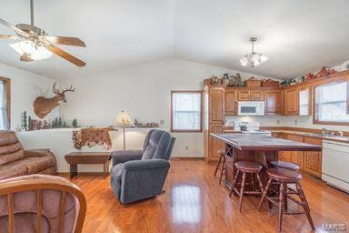 kitchen featuring light wood-style flooring, a kitchen breakfast bar, open floor plan, white appliances, and lofted ceiling