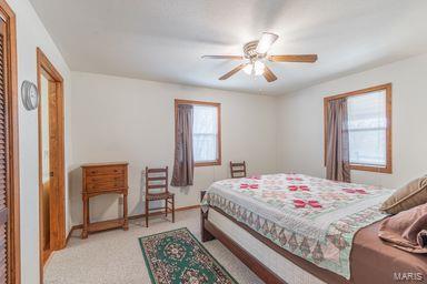 bedroom with light colored carpet, baseboards, and ceiling fan