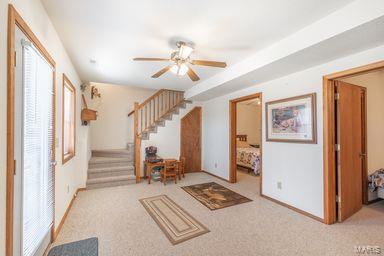 carpeted entryway with stairway, baseboards, and ceiling fan