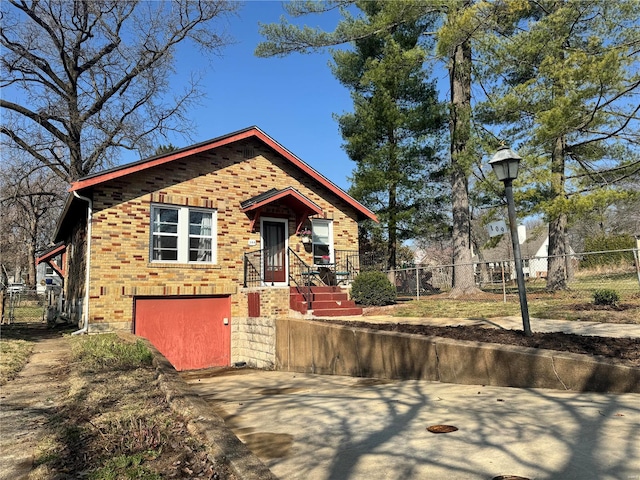 view of front of property with brick siding, driveway, an attached garage, and fence