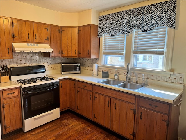 kitchen featuring range hood, a sink, light countertops, gas range, and stainless steel microwave