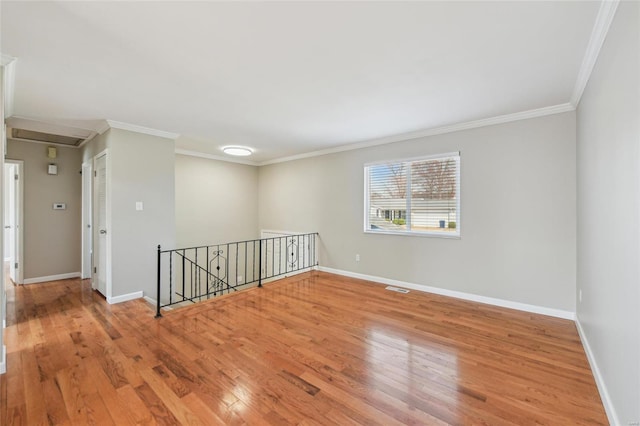 spare room featuring crown molding, baseboards, visible vents, and light wood finished floors