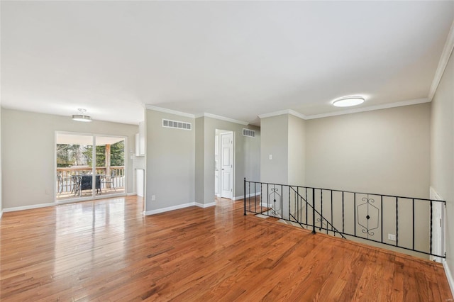 empty room featuring visible vents, baseboards, and wood finished floors