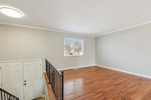 unfurnished room featuring ornamental molding, baseboards, and wood finished floors