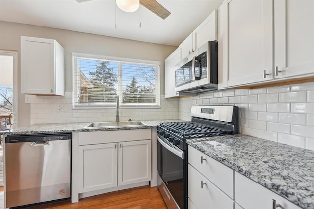 kitchen featuring a sink, white cabinets, a ceiling fan, and stainless steel appliances