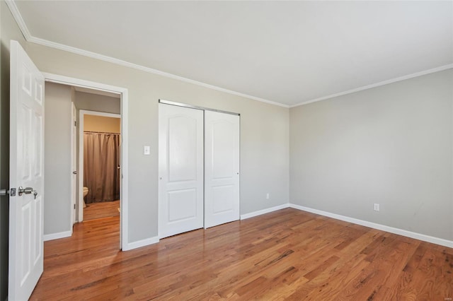 unfurnished bedroom featuring a closet, baseboards, light wood-style floors, and ornamental molding