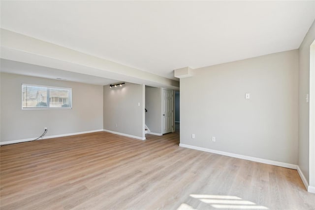 empty room featuring stairway, baseboards, and light wood-style flooring