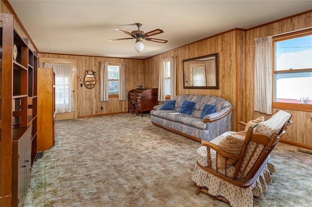 carpeted living area featuring crown molding, plenty of natural light, and wood walls