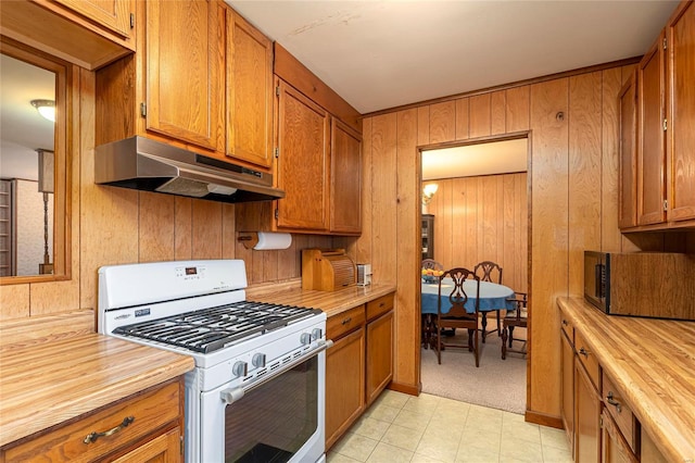 kitchen with under cabinet range hood, white range with gas cooktop, brown cabinetry, and wood counters