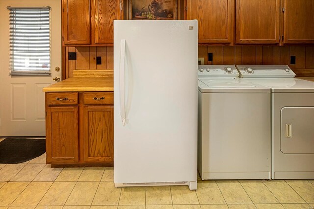 clothes washing area with light tile patterned floors, cabinet space, and washing machine and clothes dryer