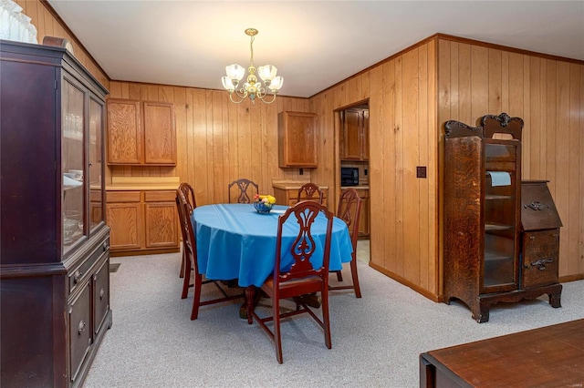 dining room with an inviting chandelier, light colored carpet, and wood walls